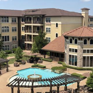 A view of a residential apartment complex with a central swimming pool and landscaped courtyard.