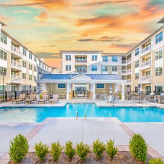 A modern apartment complex with a central swimming pool at sunset.