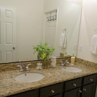 A well-organized bathroom with a granite countertop and double sinks.