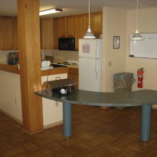 A modern kitchen with wooden cabinets and a curved countertop in an open apartment layout.
