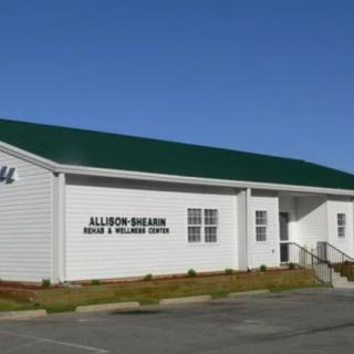A white building with a green roof, identified as a community center, on a clear day.