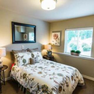 A cozy bedroom with floral bedding, overhead lighting, and a window view.
