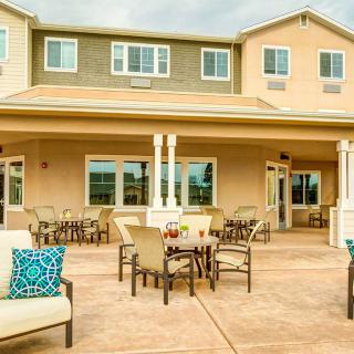 A spacious outdoor patio area with comfortable seating in front of a large house.