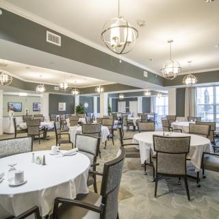 An elegant dining room with round tables and chandeliers.