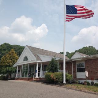 A charming building with an American flag flying in the foreground under a partly cloudy sky.