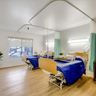 A modern hospital patient room featuring two beds, bright lighting, and a clean aesthetic.