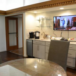 A modern kitchen interior featuring a coffee maker and a mounted television.