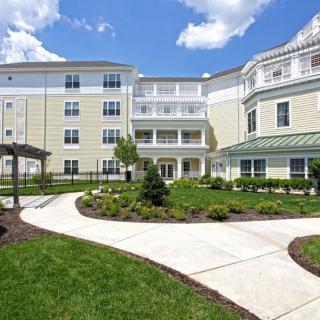 A modern residential building with well-maintained landscaping and a paved walkway.