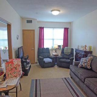 A cozy living room with a sofa, armchairs, and a television.