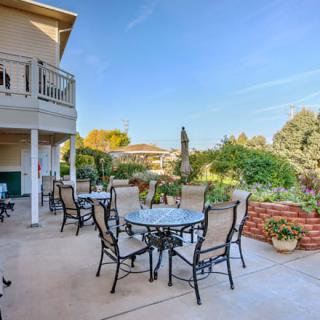 Spacious outdoor patio with tables and chairs overlooking a lush garden.