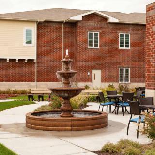 A tranquil courtyard with a central fountain surrounded by outdoor seating and a brick building backdrop.