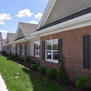 A row of single-story residential buildings with brick exteriors and well-maintained landscaping.