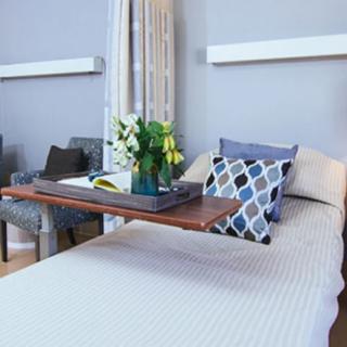 A hospital room with a bed and a tray table featuring flowers.