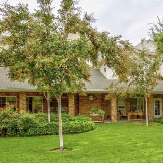 A charming brick house with a well-maintained garden and lush green lawn.