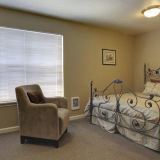 Cozy bedroom with a metal bed frame and an upholstered chair by the window.