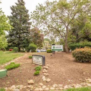 A landscaped park area with signs and various trees providing greenery.