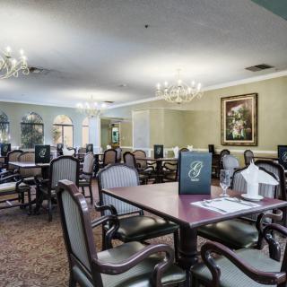 An elegant, empty dining room with chandeliers and well-arranged tables and chairs.