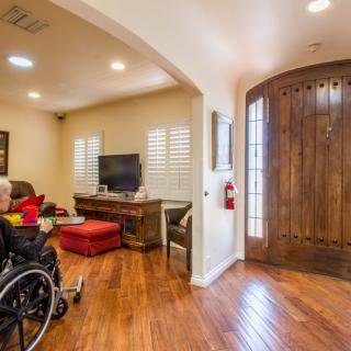 A cozy living room with a wheelchair, hardwood floors, and a television set.