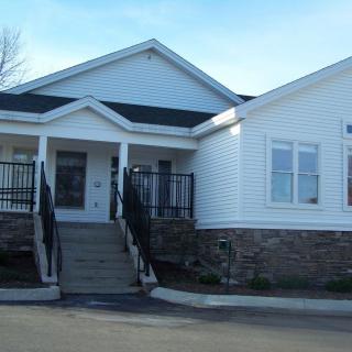 A view of a residential building with a front porch and steps.