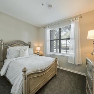 A cozy bedroom with a wooden bed, white bedding, and soft lighting.