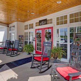 A welcoming porch with red-cushioned rocking chairs and potted plants by the entrance.