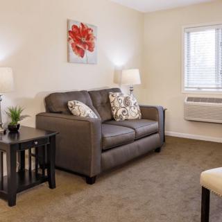 A cozy living room with a comfortable sofa, two lamps, and a vibrant piece of artwork on the wall.