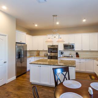 A modern kitchen with white cabinets, granite countertops, and stainless steel appliances.