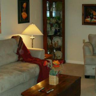 A cozy living room with a sofa, lamp, and coffee table adorned with decor and artwork on the walls.