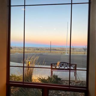 A view of the sunset through a window, featuring a bench and vast landscape.