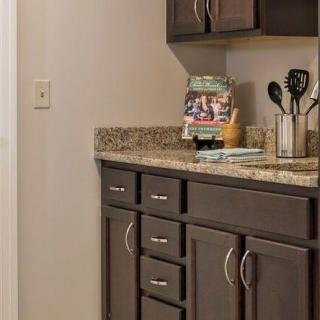 A modern kitchen with dark cabinets and a granite countertop, featuring utensils and a cookbook display.