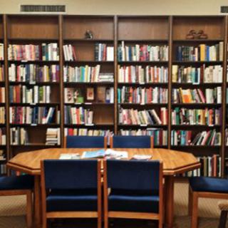 A cozy library reading area with a table and chairs surrounded by bookshelves.