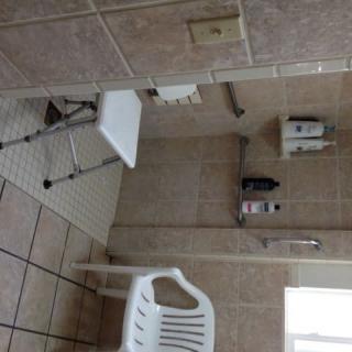 An accessible bathroom with a shower chair and tiled walls.