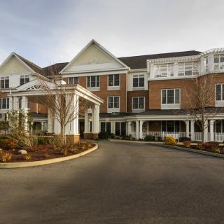 A large residential building with a driveway and landscaped surroundings.