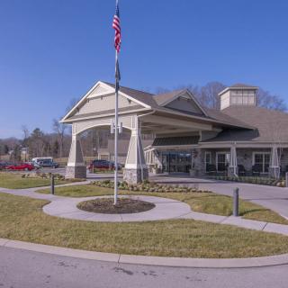 A building with a large entrance and an American flag in front, surrounded by landscaped pathways under a clear blue sky.