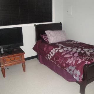 A small bedroom with a single bed and a TV on the nightstand.