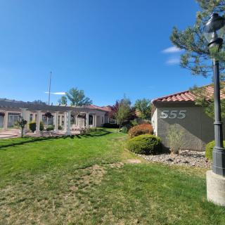 A sunny landscape featuring a building with manicured lawns and trees.