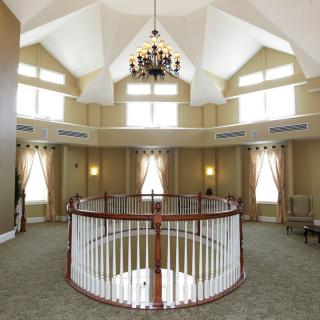 A spacious interior with vaulted ceilings, a central chandelier, and an upper-level balcony with railing.