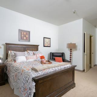 A cozy bedroom with a large bed, decorative pillows, and a stylish lamp in a well-furnished setting.