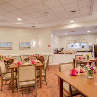 A cozy dining area with neatly arranged tables and chairs, featuring soft lighting and warm decor.