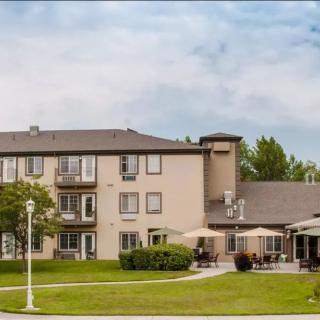 A view of a residential building with an outdoor patio and a well-maintained lawn.