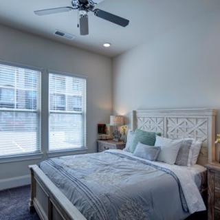 A cozy bedroom with a neatly made bed and a ceiling fan.