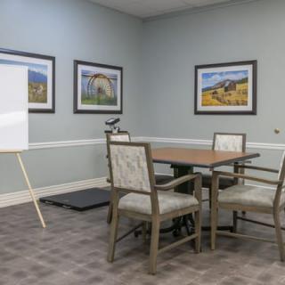 A small meeting room with a conference table, chairs, and a whiteboard.