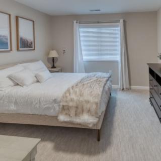 A cozy bedroom with a large bed, two paintings on the wall, and a window with curtains.