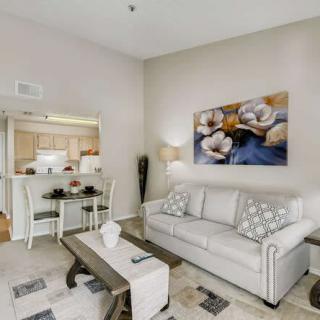 A modern living room featuring a comfortable sofa, stylish coffee table, and a scenic view of the adjacent kitchen and dining area.