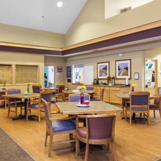 A spacious dining area with neatly arranged tables and chairs, featuring decorated walls and ambient lighting.