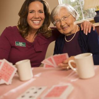 Two women enjoying a game of cards together indoors, sharing smiles and companionship.
