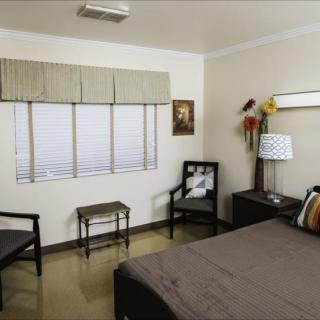 A tidy bedroom with a bed, chairs, and decorative elements.