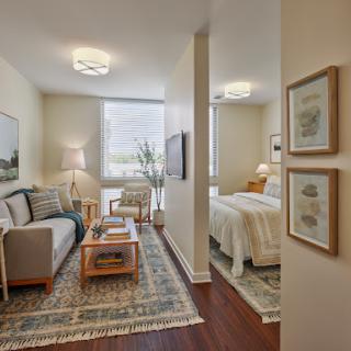 A cozy and modern living space seamlessly blending a living room and bedroom, adorned with warm lighting and stylish decor.