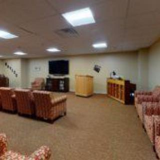 A conference room with comfortable seating, a television, and a podium.