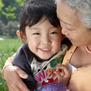 An elderly woman hugs a smiling child outdoors, capturing a loving family moment.